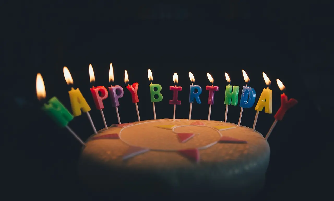 Lit letter-shaped candles spelling Happy Birthday on a cake