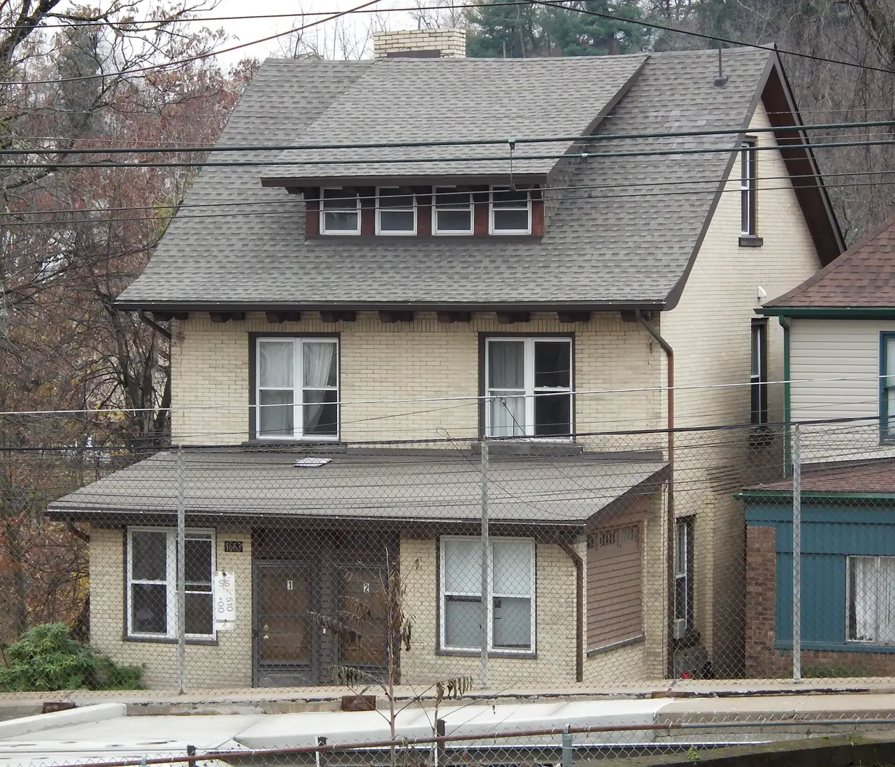 A two-storey brick and stucco house with a dormer window and porch
