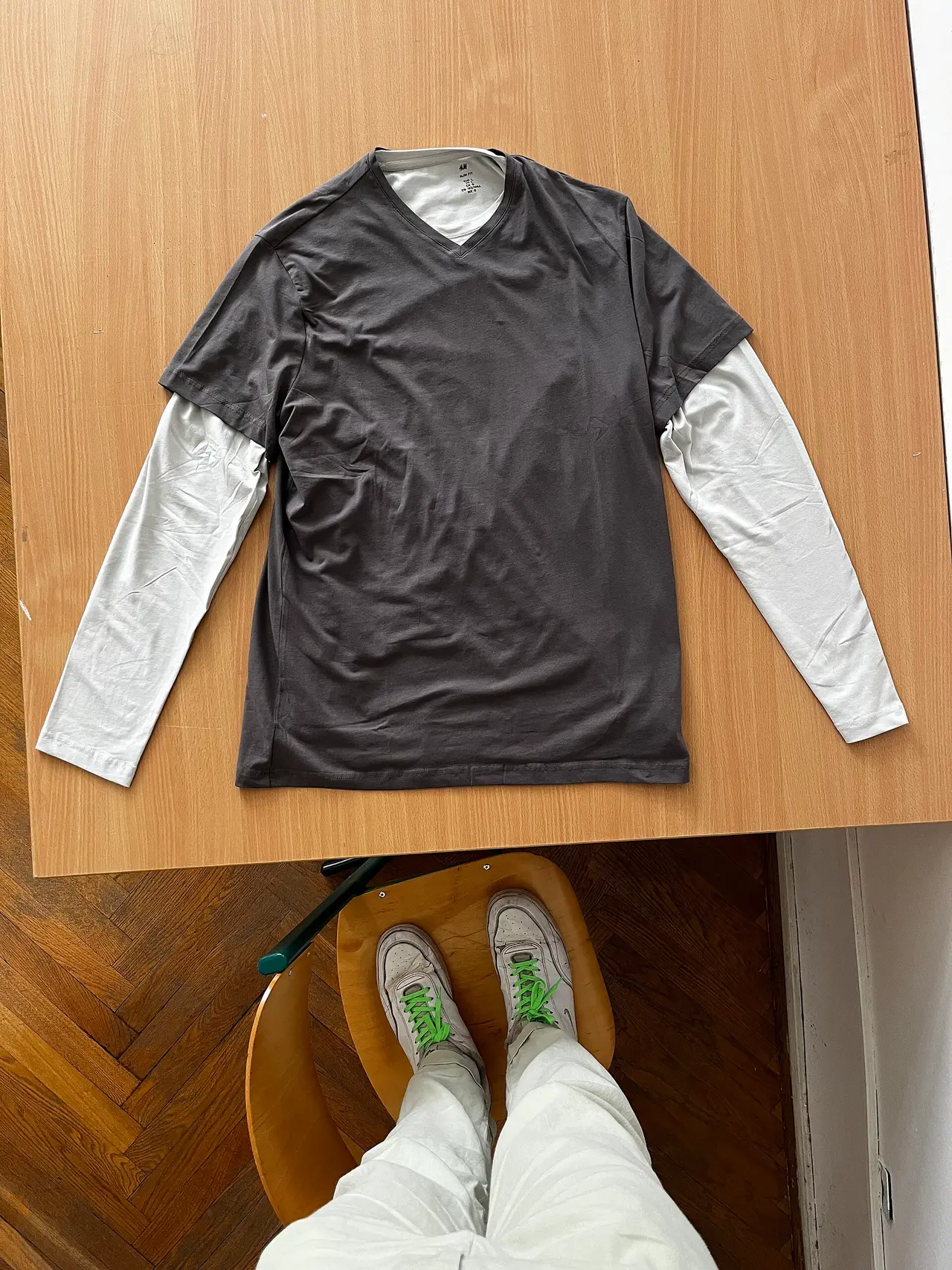 Layered dark and white long-sleeved shirt laid flat on a wooden table