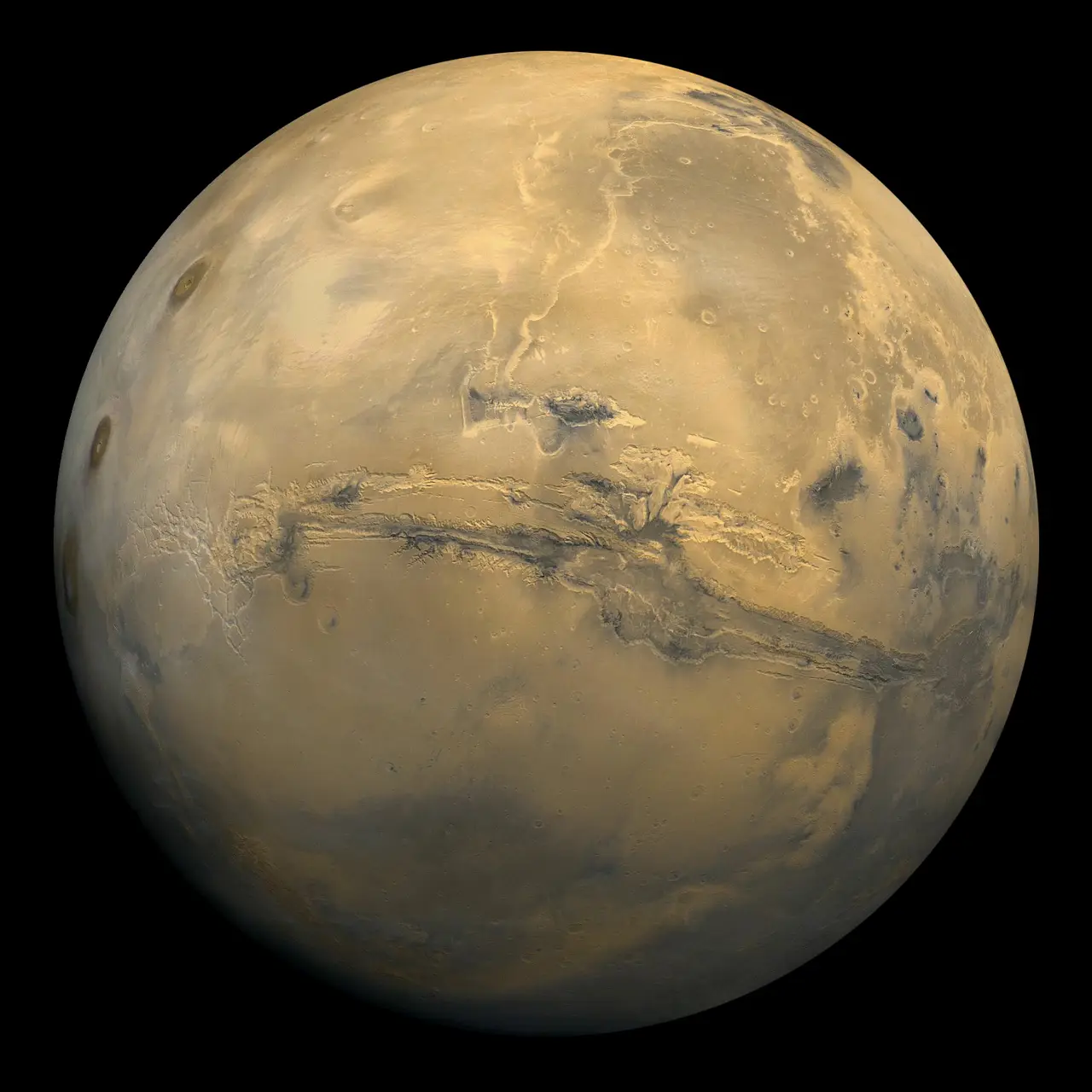 The planet Mars as an orange globe with a long dark canyon across it