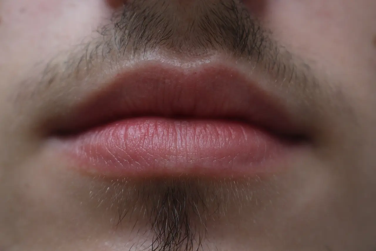 Close-up of closed lips with a moustache and stubble