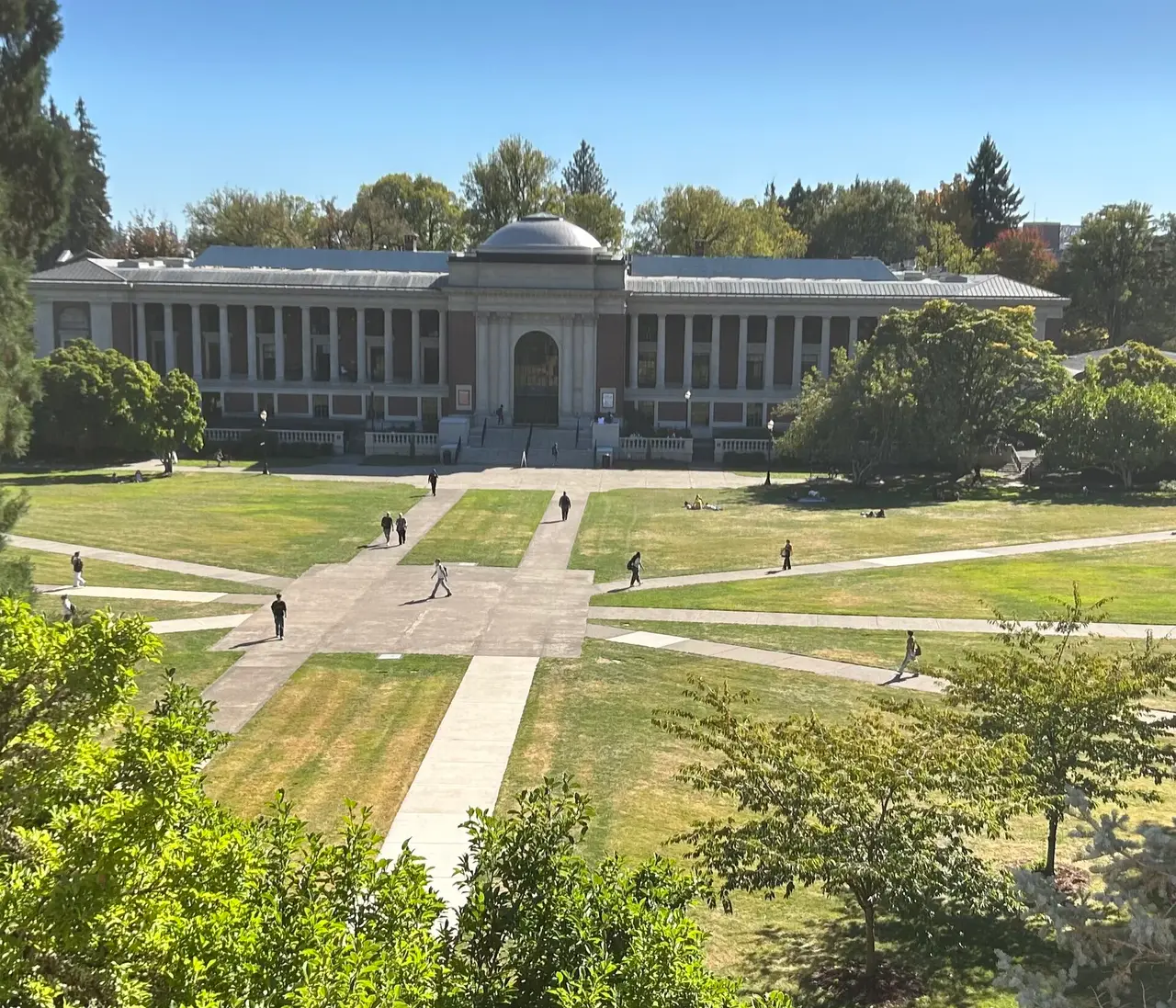 Large stone building across a lawn with crossing paths