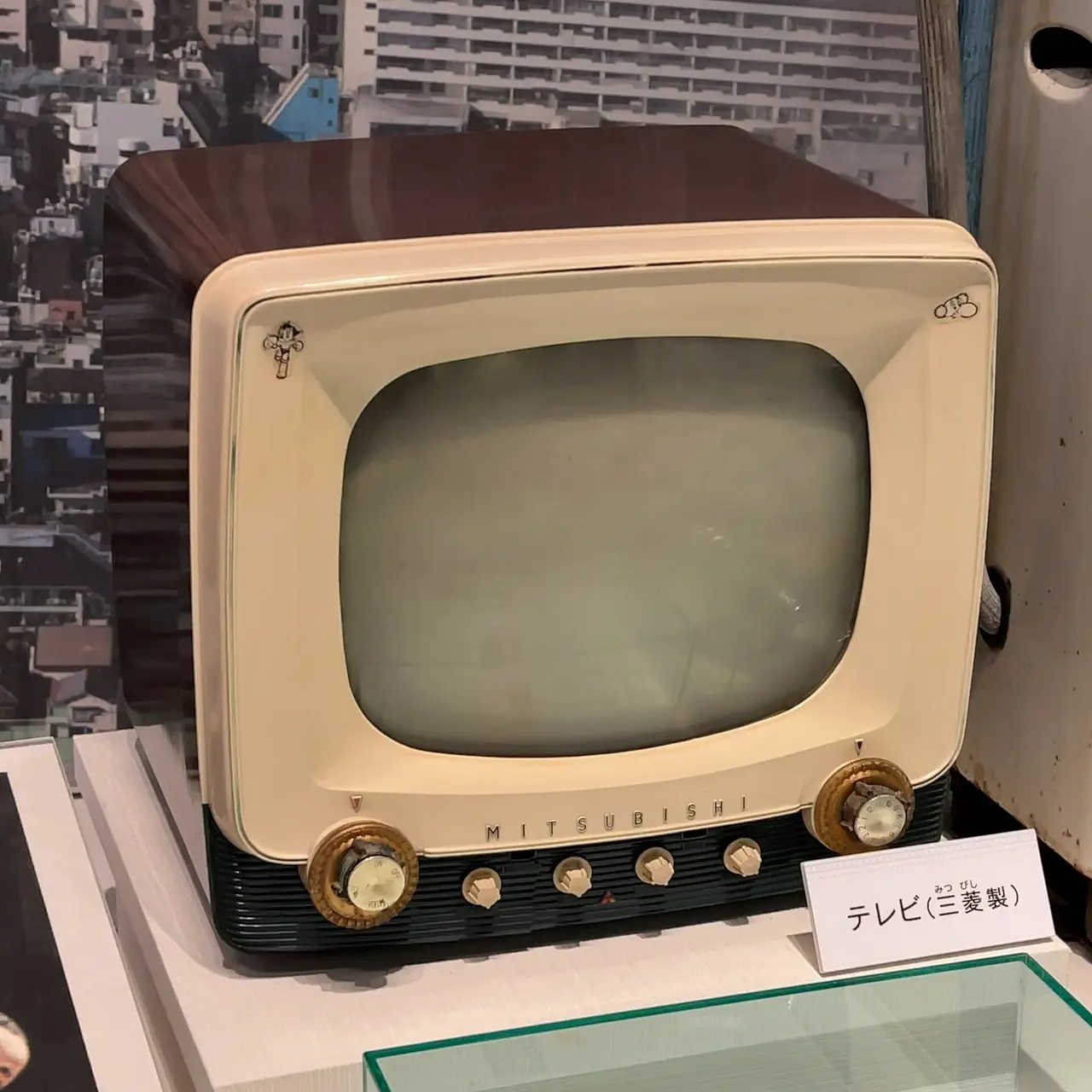 An old cream and brown Mitsubishi television on a museum stand