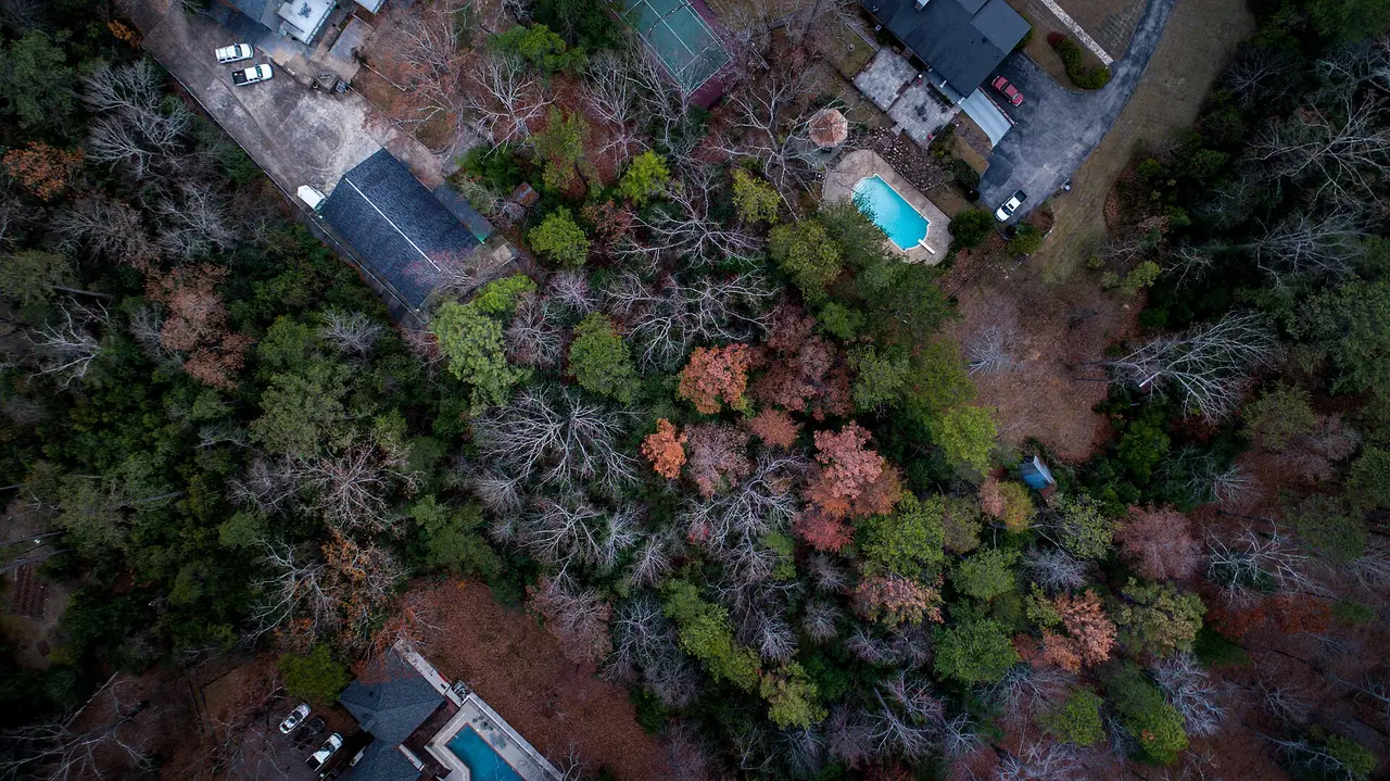 Aerial view of houses with pools among trees in autumn colours