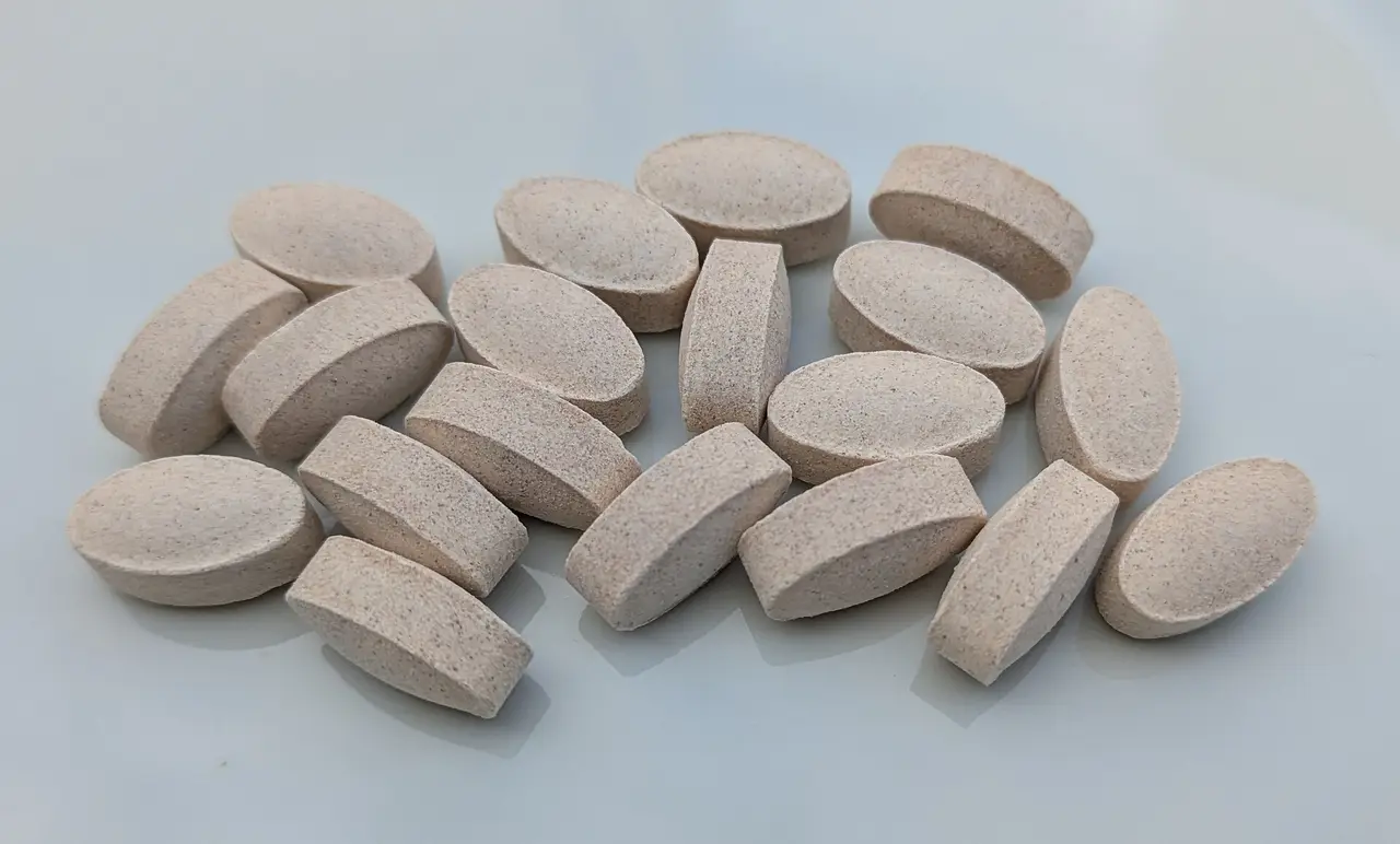 Pale oval vitamin tablets lying on a grey-blue surface