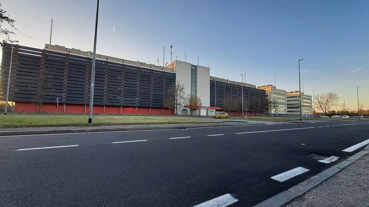 A long dark industrial building beside an empty road at dusk