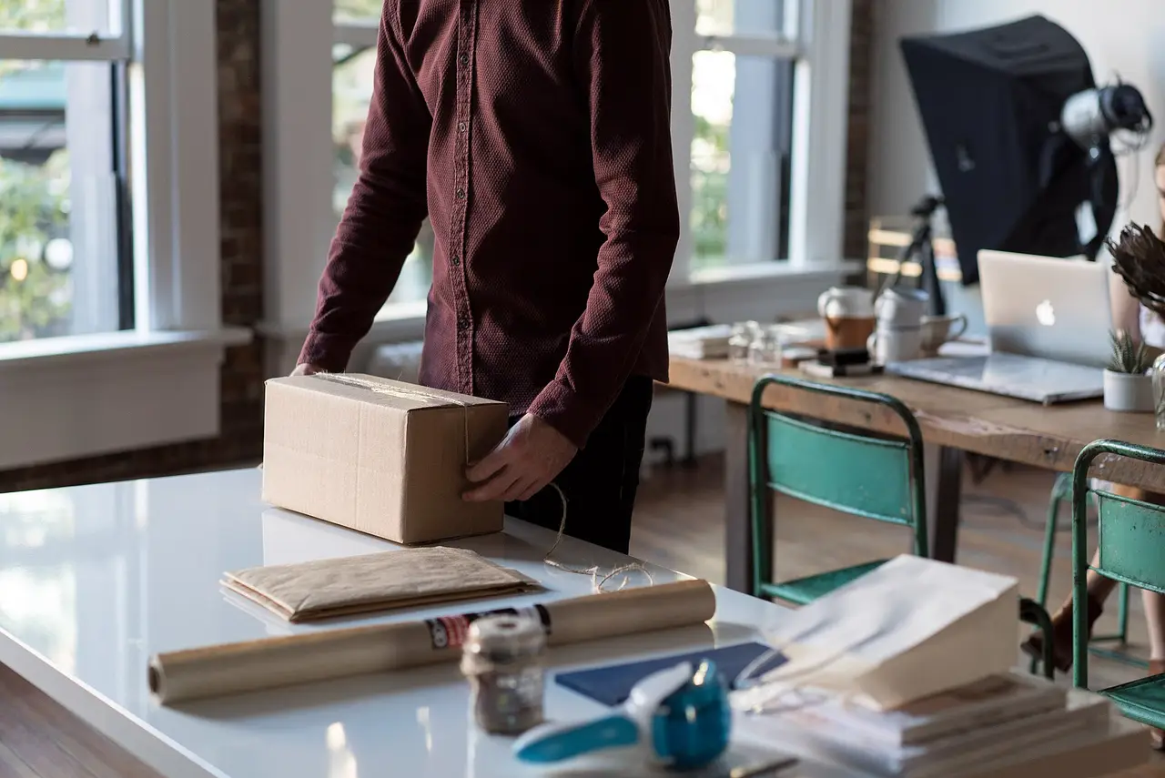 A person packing a cardboard parcel on a white table in an office
