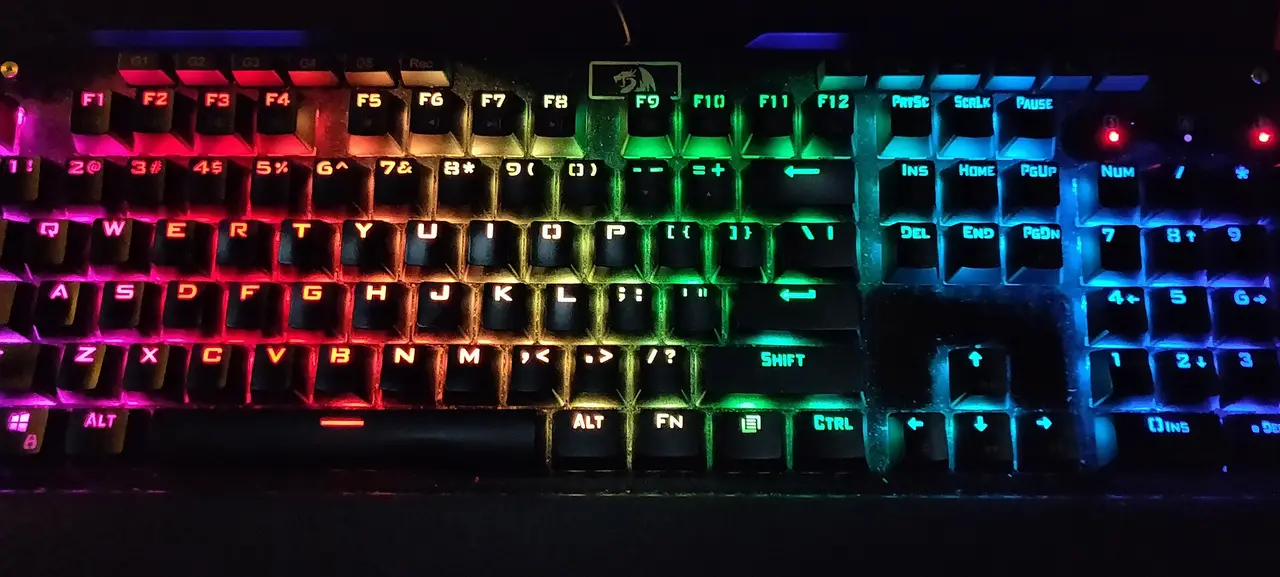 A computer keyboard with keys lit in rainbow colours