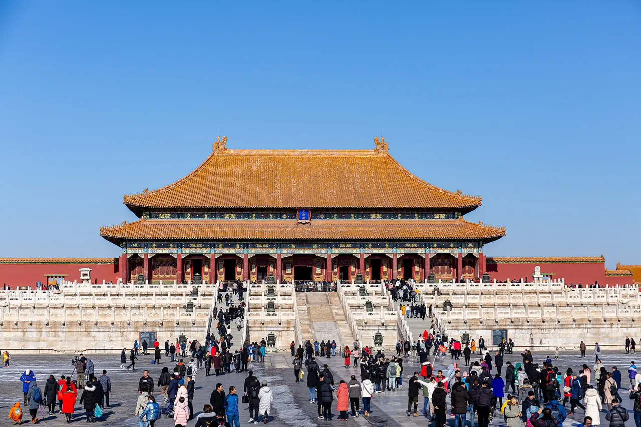 A yellow-roofed palace hall above a courtyard with visitors