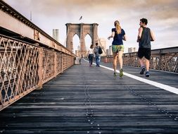 young people running on bridge in city