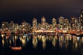 night skyline with city mirroring on water, canada, vancouver