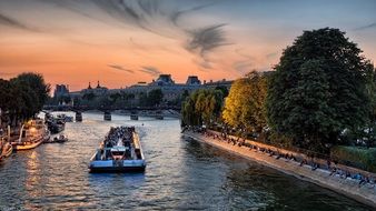 boats on water and people on bank of seine river at sunset, france, paris