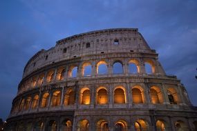 lilluminated colosseum ruin at cloudy evening sky, italy, rome