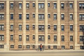 young boy with bicycle stands at brick building