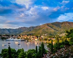 picturesque old town on mountains at lake with ships and boats at port, montenegro