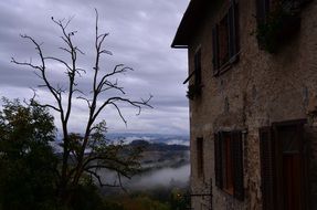 old house in view of foggy hills at dusk, italy