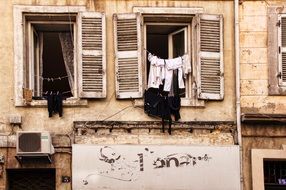 clothing hanging on lines from windows on grunge facade, france, marseille