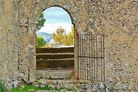 beautiful landscape view through open iron gate in old stone wall, spain, mallorca