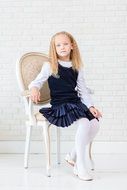 pretty child girl with blue eyes sits on chair