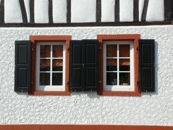 red windows with black shutters on white facade