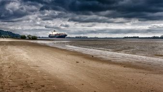 sand beach of elbe river and ships on water at port, germany, hamburg