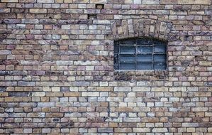 small grated window on old brick wall