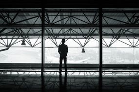 waiting man, silhouette in terminal at window above airplanes