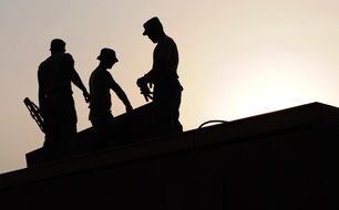 three men silhouettes on roof at sky, construction workers