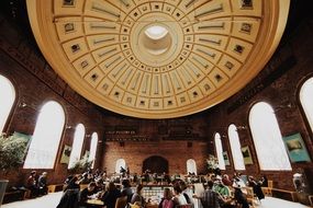 people in hall with brick walls under impressive dome