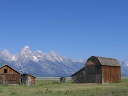 old wooden farm buildings on meadow at mountains, usa, wyoming, grand tetons