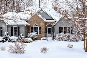 snow covered front yard of brick village house