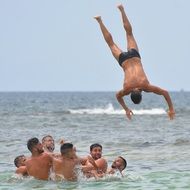 jumping man above happy young men in sea