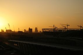 construction cranes in city at sunset sky, uk, england, london