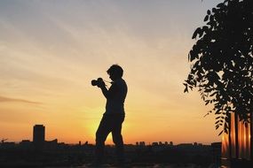 photographer, silhouette with camera at evening sky