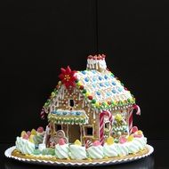 beautiful gingerbread house, colorful christmas pastries at dark background