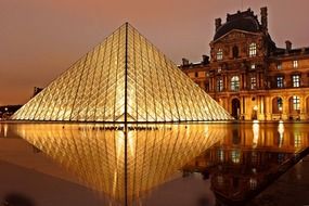 night view of louvre pyramid with reflection on water, france, paris