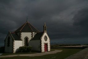 small white church building under dark stormy clouds