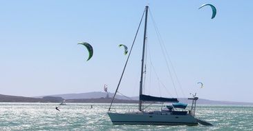 paragliders at sailing boat on sea, south africa, cape town