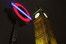 London Underground sign and Big Ben in London by night