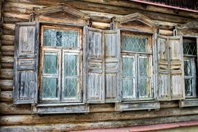 grated windows with shutters on facade of old wooden house, russia, abramtzevo