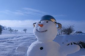 happy snowman with carrot nose and pot on head in winter landscape