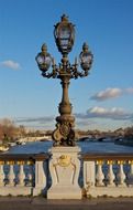 antique lamp post on bridge across river, france, paris
