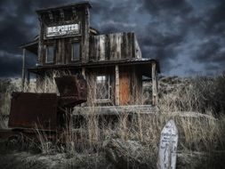 rusty wagon in front of old wooden building ruin at cloudy sky