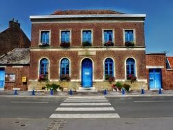 old red brick building with blue doors and windows at road, france, bellaing
