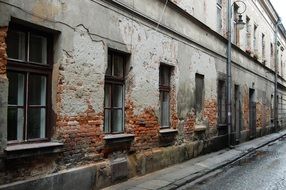 old brick building with damaged plaster on facade, poland