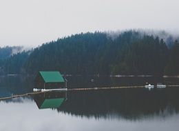 small fishing house on calm water at foggy forest on mountain