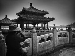 woman in hat taking photo of pagoda