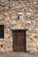 closed old wooden door in stone wall