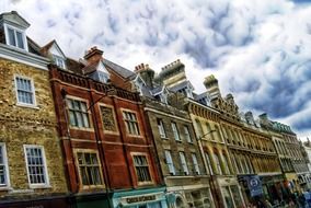 row of colorful old brick buildings at cloudy sky, uk, england, cambridge