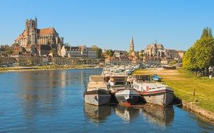 boats on water in view of old city among colorful nature at yonne river, france, auxerre